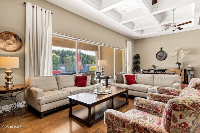 living room with a towering ceiling, hardwood / wood-style floors, coffered ceiling, ceiling fan, and beam ceiling