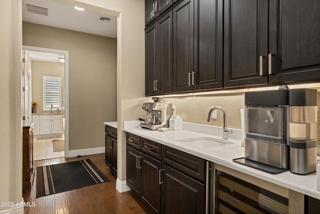 kitchen with wine cooler, sink, dark wood-type flooring, and dark brown cabinets