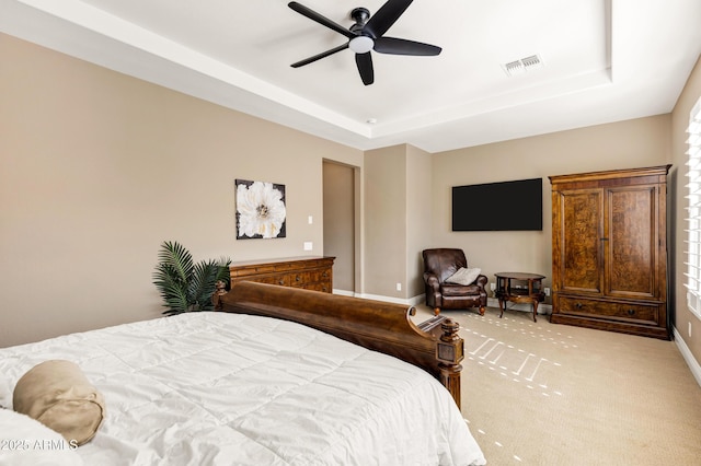 bedroom featuring ceiling fan, light colored carpet, and a raised ceiling