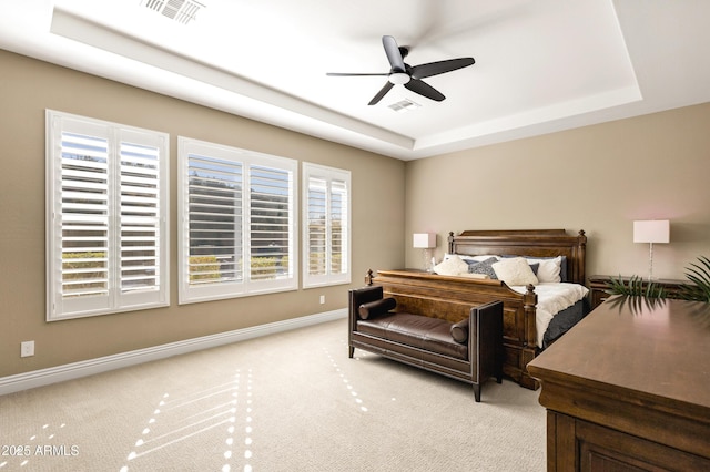 bedroom with light carpet, ceiling fan, and a tray ceiling