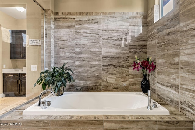 bathroom featuring vanity and tiled bath