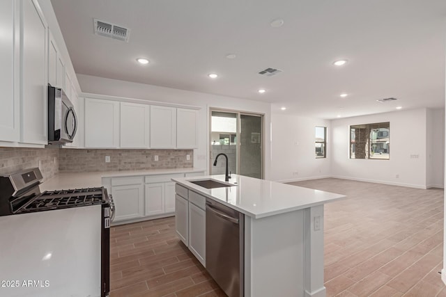 kitchen featuring a center island with sink, visible vents, white cabinets, appliances with stainless steel finishes, and light countertops