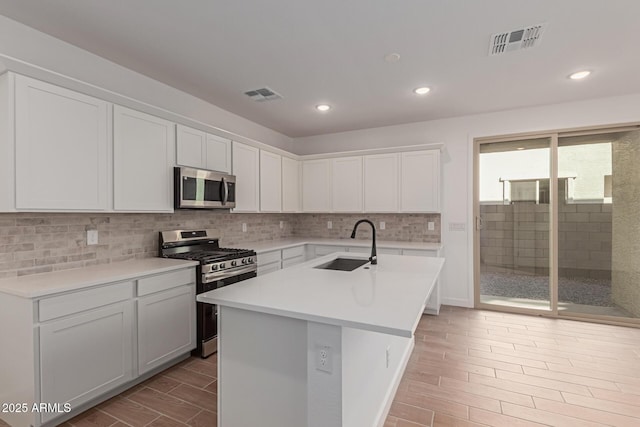 kitchen with appliances with stainless steel finishes, light countertops, visible vents, and a sink