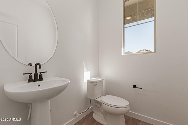 bathroom featuring toilet, baseboards, and wood finished floors