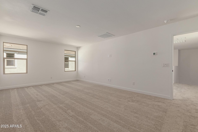 spare room with visible vents, light carpet, and baseboards