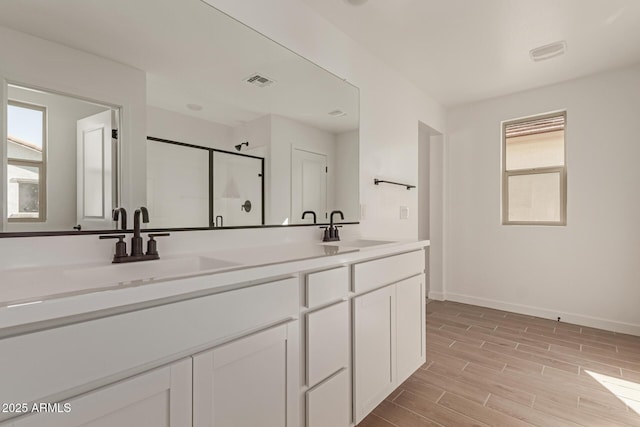 bathroom with wood finish floors, a sink, visible vents, and a stall shower