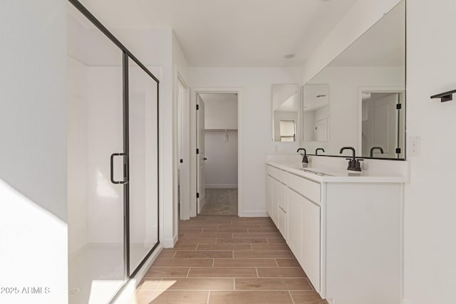 full bath with a shower stall, a spacious closet, vanity, and wood finish floors