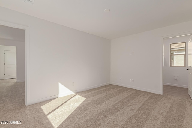 spare room with light carpet and baseboards