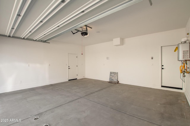 garage featuring water heater, a garage door opener, and baseboards