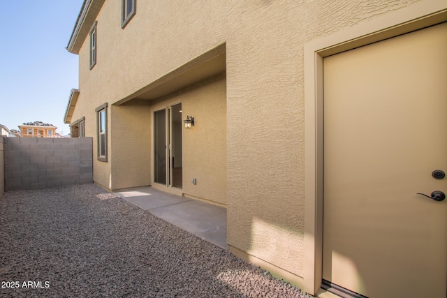 exterior space with a patio area, fence, and stucco siding