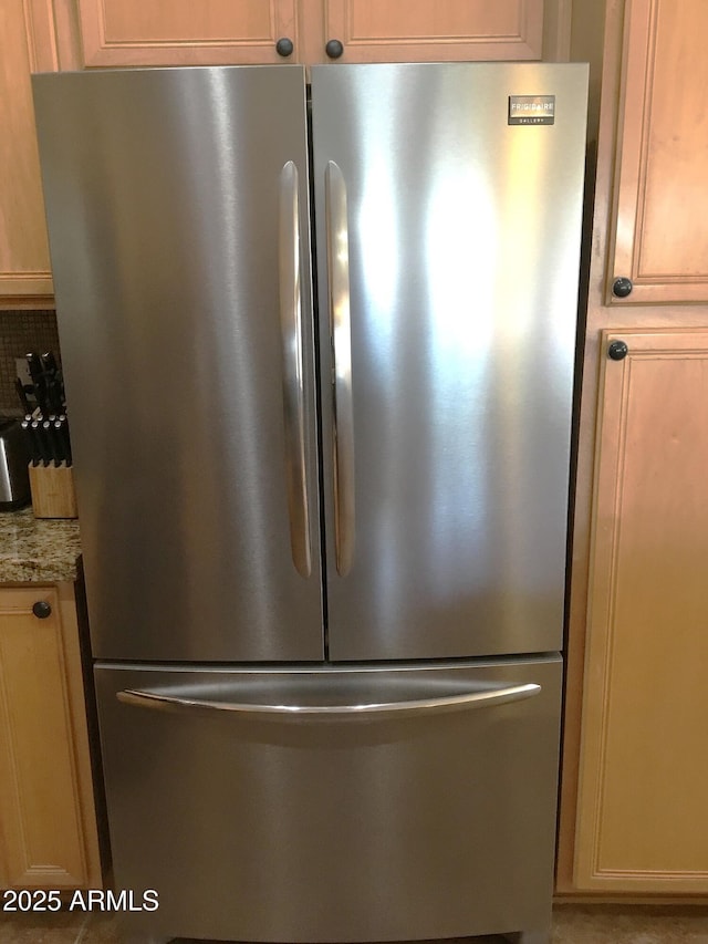 interior details featuring stainless steel refrigerator and light stone countertops