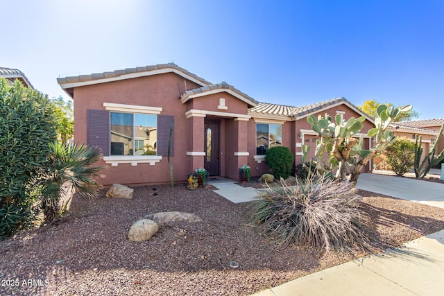 view of front of property with concrete driveway, stucco siding, a tiled roof, and a garage