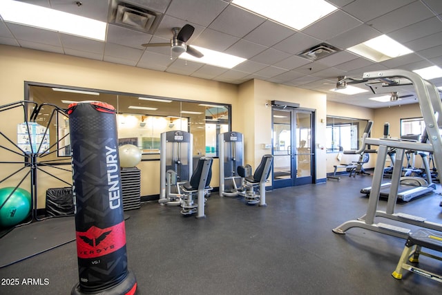 exercise room featuring a paneled ceiling, french doors, and ceiling fan