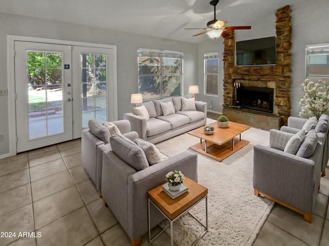 tiled living room featuring a stone fireplace, french doors, and ceiling fan