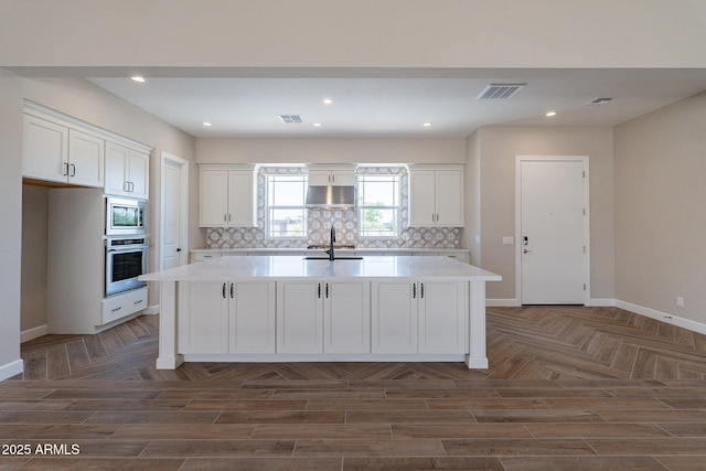 kitchen featuring visible vents, decorative backsplash, appliances with stainless steel finishes, white cabinets, and under cabinet range hood