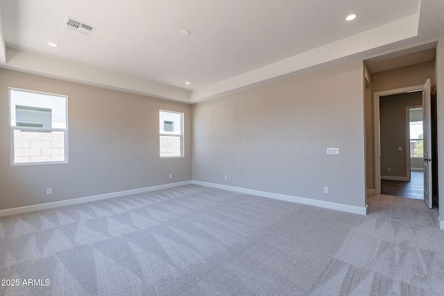 spare room featuring light carpet, baseboards, visible vents, a raised ceiling, and recessed lighting