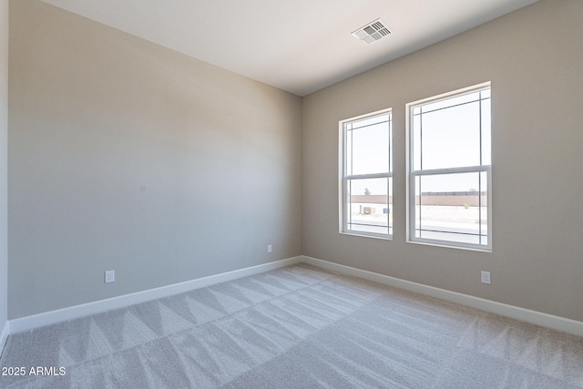 empty room featuring visible vents, light carpet, and baseboards