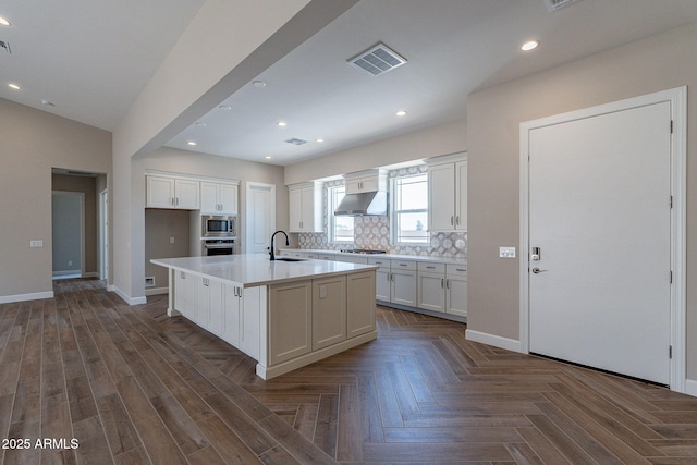 kitchen with visible vents, appliances with stainless steel finishes, white cabinetry, a sink, and under cabinet range hood