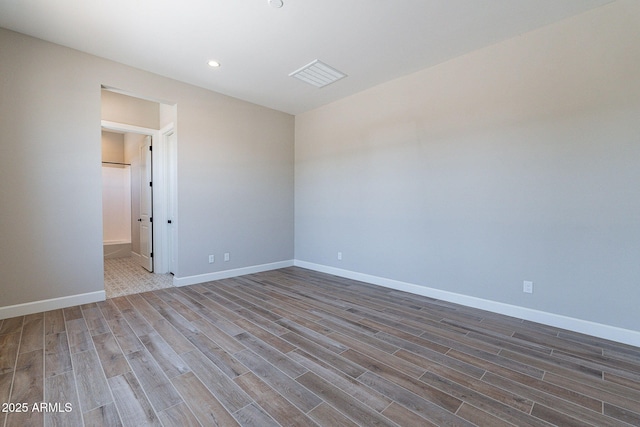 empty room with recessed lighting, wood finished floors, visible vents, and baseboards