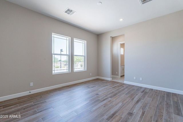 spare room featuring visible vents, baseboards, and wood finished floors