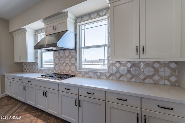 kitchen with a wealth of natural light, white cabinetry, stainless steel gas stovetop, and under cabinet range hood