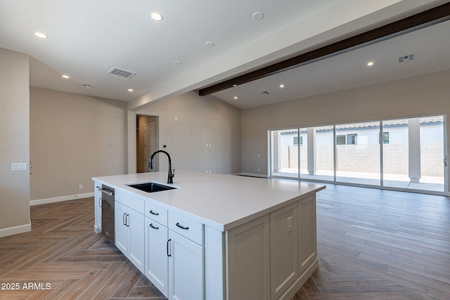 kitchen featuring visible vents, beamed ceiling, a kitchen island with sink, a sink, and recessed lighting