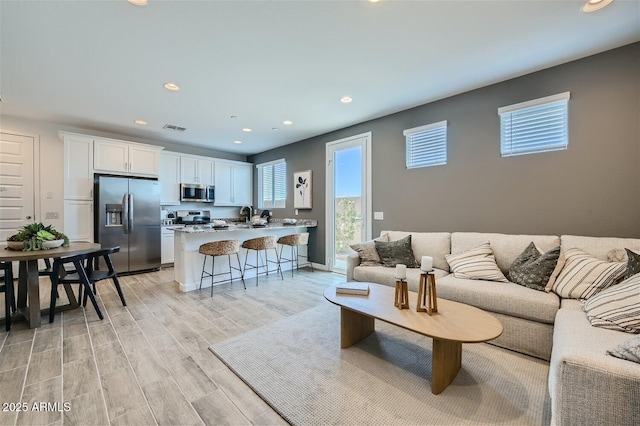 living room with recessed lighting, visible vents, and light wood-type flooring
