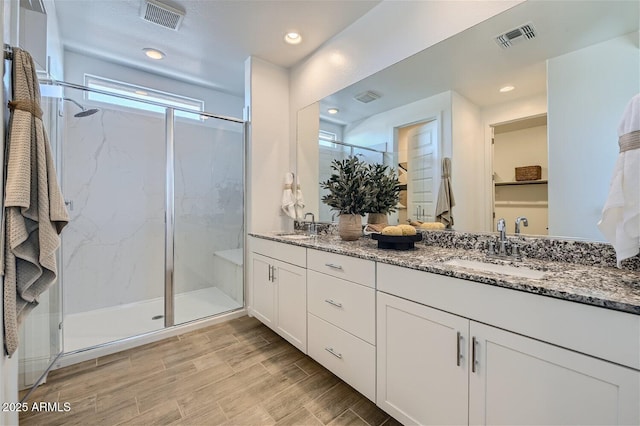 full bath with visible vents, a sink, and a marble finish shower