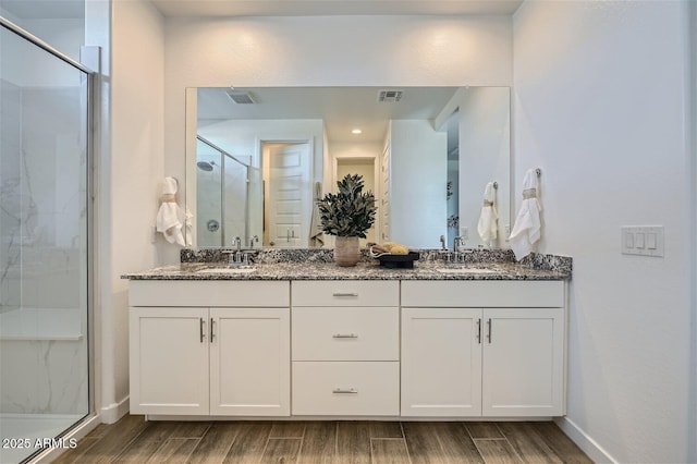 full bathroom featuring wood finished floors, visible vents, a sink, and a stall shower