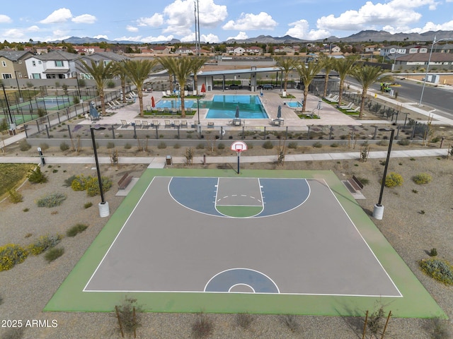 view of sport court featuring a mountain view, fence, community basketball court, and a residential view