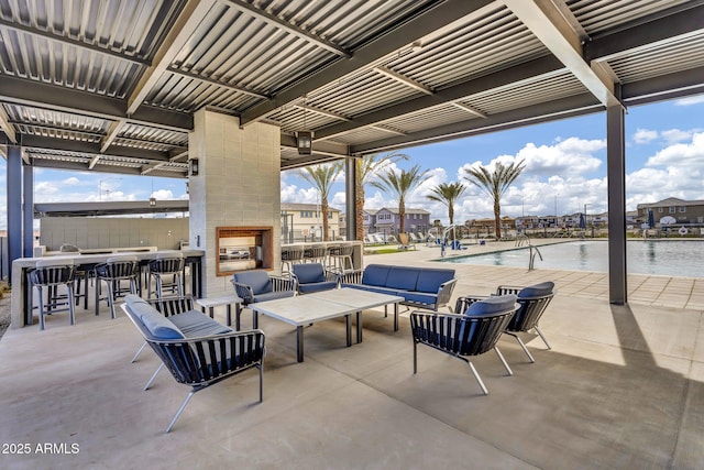 view of patio / terrace featuring a community pool, an outdoor living space with a fireplace, and outdoor dry bar