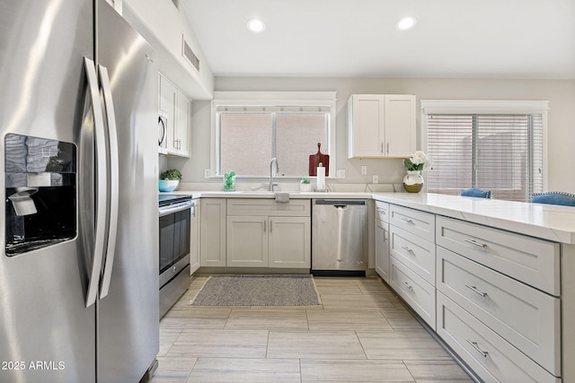 kitchen with white cabinetry, appliances with stainless steel finishes, kitchen peninsula, and sink