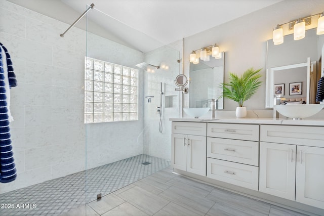 bathroom with vanity, vaulted ceiling, and tiled shower