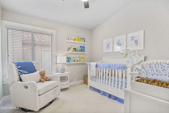 bedroom featuring a crib, ceiling fan, and vaulted ceiling