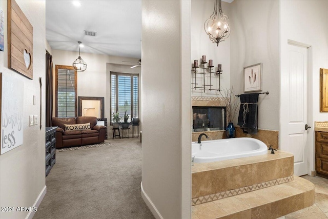 bathroom with vanity, a relaxing tiled tub, and ceiling fan