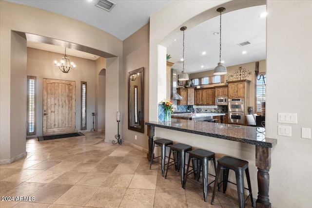 kitchen featuring kitchen peninsula, a kitchen breakfast bar, decorative backsplash, stainless steel appliances, and decorative light fixtures