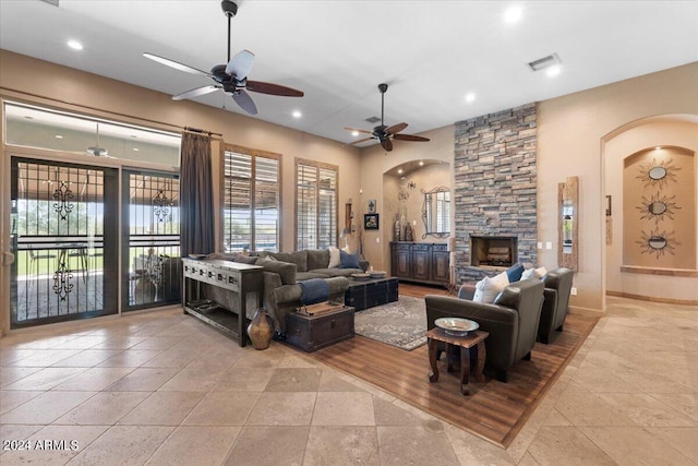 living room with a stone fireplace and ceiling fan