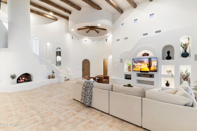 living room featuring ceiling fan, built in features, a fireplace, and a high ceiling