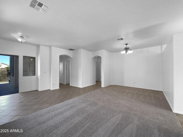 tiled empty room featuring a chandelier