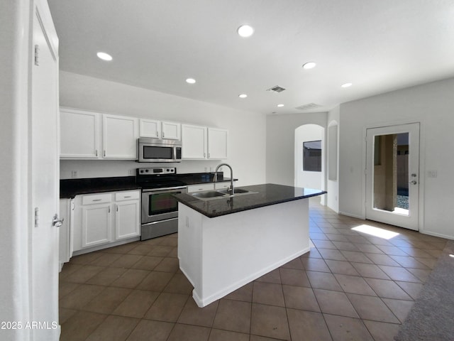 kitchen featuring appliances with stainless steel finishes, white cabinetry, a center island with sink, and sink