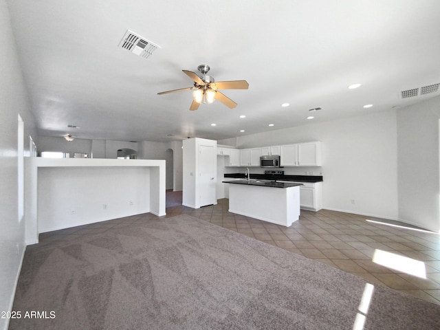 kitchen with white cabinets, ceiling fan, dark tile patterned flooring, and sink