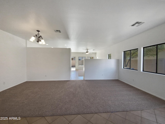 spare room with ceiling fan with notable chandelier, tile patterned floors, and a healthy amount of sunlight