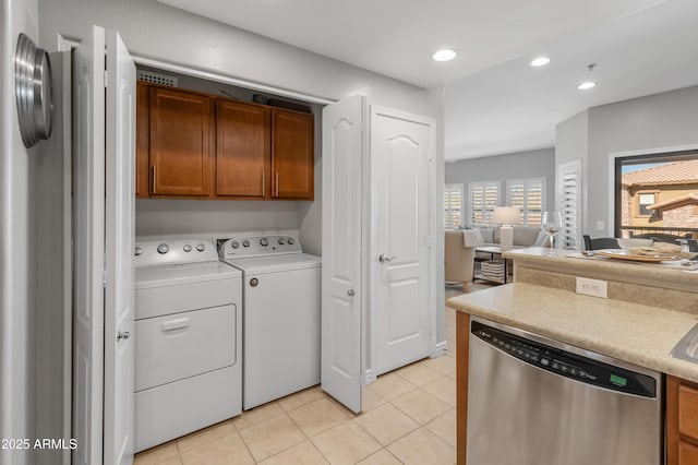 laundry area with independent washer and dryer, cabinets, and light tile patterned floors