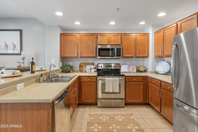 kitchen with appliances with stainless steel finishes, kitchen peninsula, light tile patterned flooring, and sink