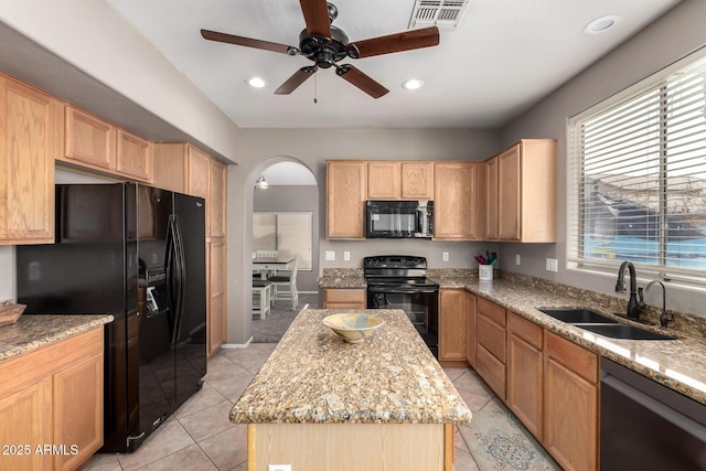 kitchen with a center island, sink, light stone countertops, and black appliances