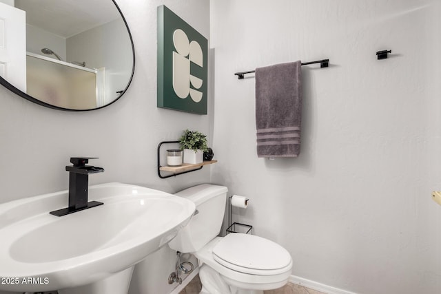 bathroom featuring sink, a shower with door, and toilet