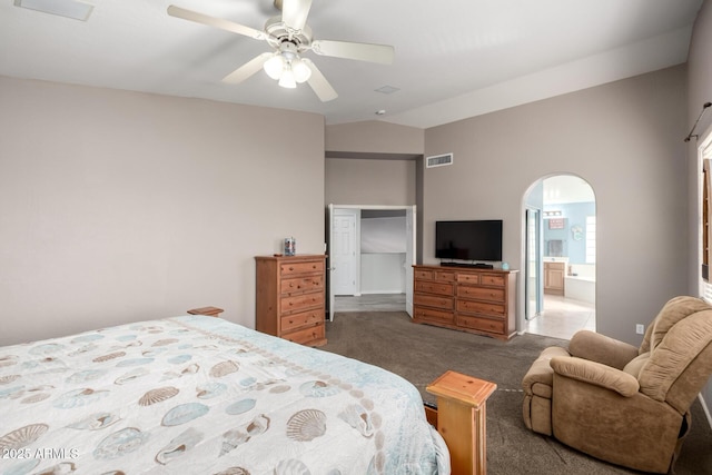 bedroom with vaulted ceiling, ensuite bathroom, ceiling fan, and dark colored carpet