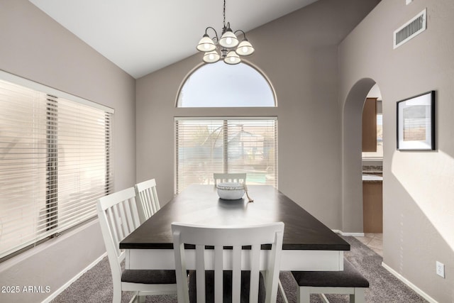 carpeted dining area featuring an inviting chandelier and vaulted ceiling