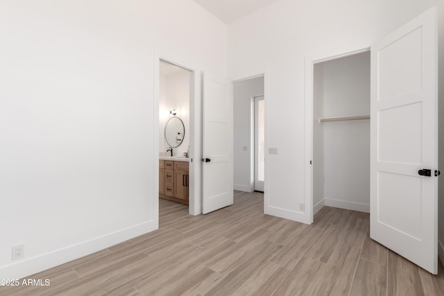 unfurnished bedroom featuring light wood finished floors, baseboards, a closet, and a sink