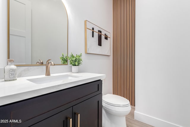 bathroom featuring toilet, vanity, and wood finished floors